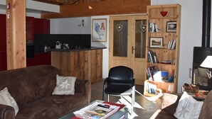 A cozy living room with a brown sofa, a black chair, a wooden bookshelf, and a fireplace. - Recent cozy chalet 10 pers near slopes (Pralognan-la-Vanoise)