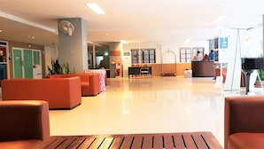 A spacious lobby with a reception desk, seating area, and a grand piano. - Plaza Residence Jomtien Beach (Pattaya)