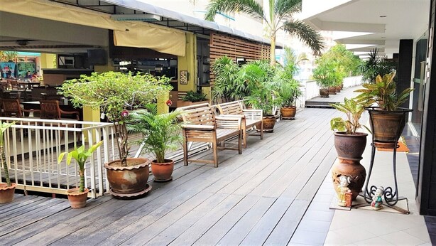 A wooden deck with potted plants, wooden benches, and a white railing. - Plaza Residence Jomtien Beach (Pattaya)