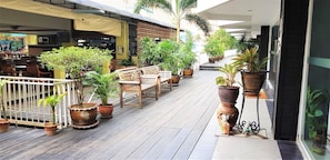 A wooden deck with potted plants, wooden benches, and a white railing.