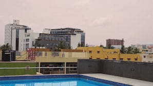 Una piscina con vista a edificios circundantes, incluyendo un hotel llamado "Delta" y otro edificio identificado como "Beta".