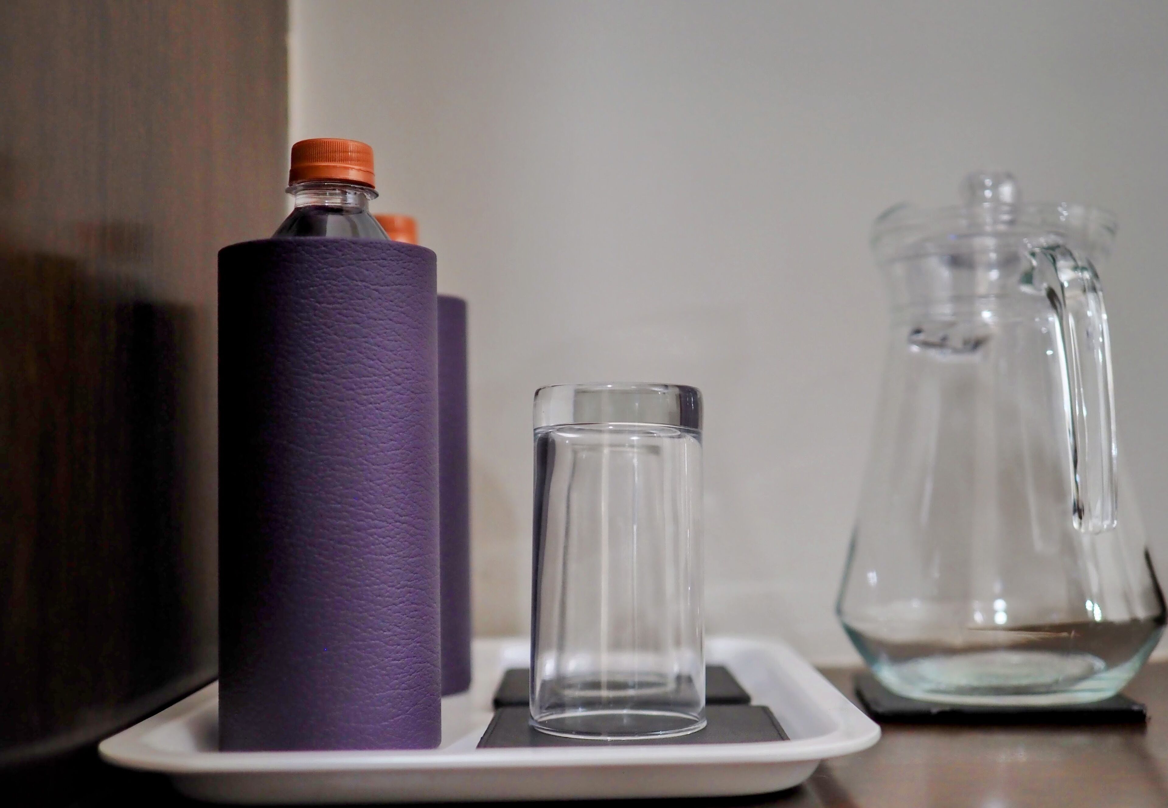 A bottle, a glass, and a pitcher on a tray.