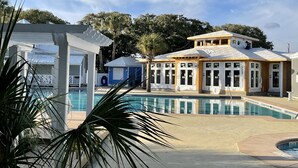 A pool area with a covered pavilion, a building under construction, and a view of the surrounding trees.