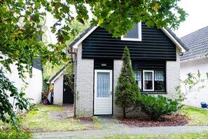 Une maison à deux étages, avec un toit noir et des murs extérieurs blancs.