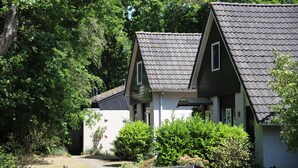 A row of small, two-story houses with sloped roofs, surrounded by greenery and a wooden fence with the number 5.