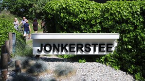 A sign reading "JONKERSTEE" with a gravel path and cacti in front.