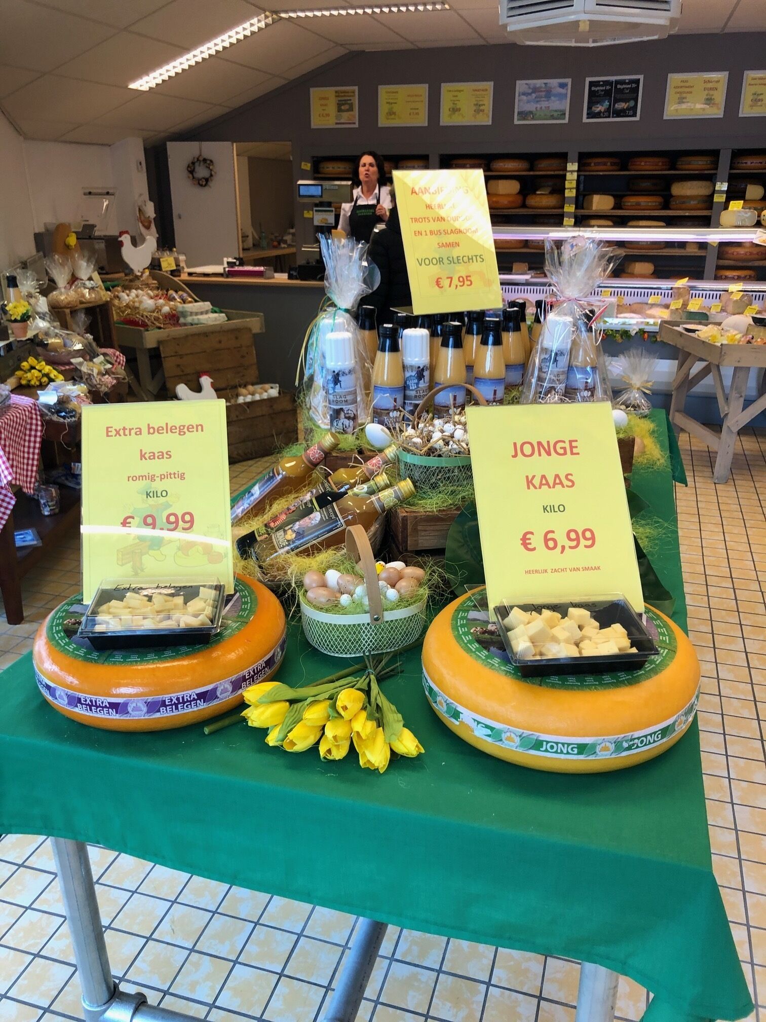 Un présentoir de fromages avec des panneaux indiquant les prix et les différents types de fromages.