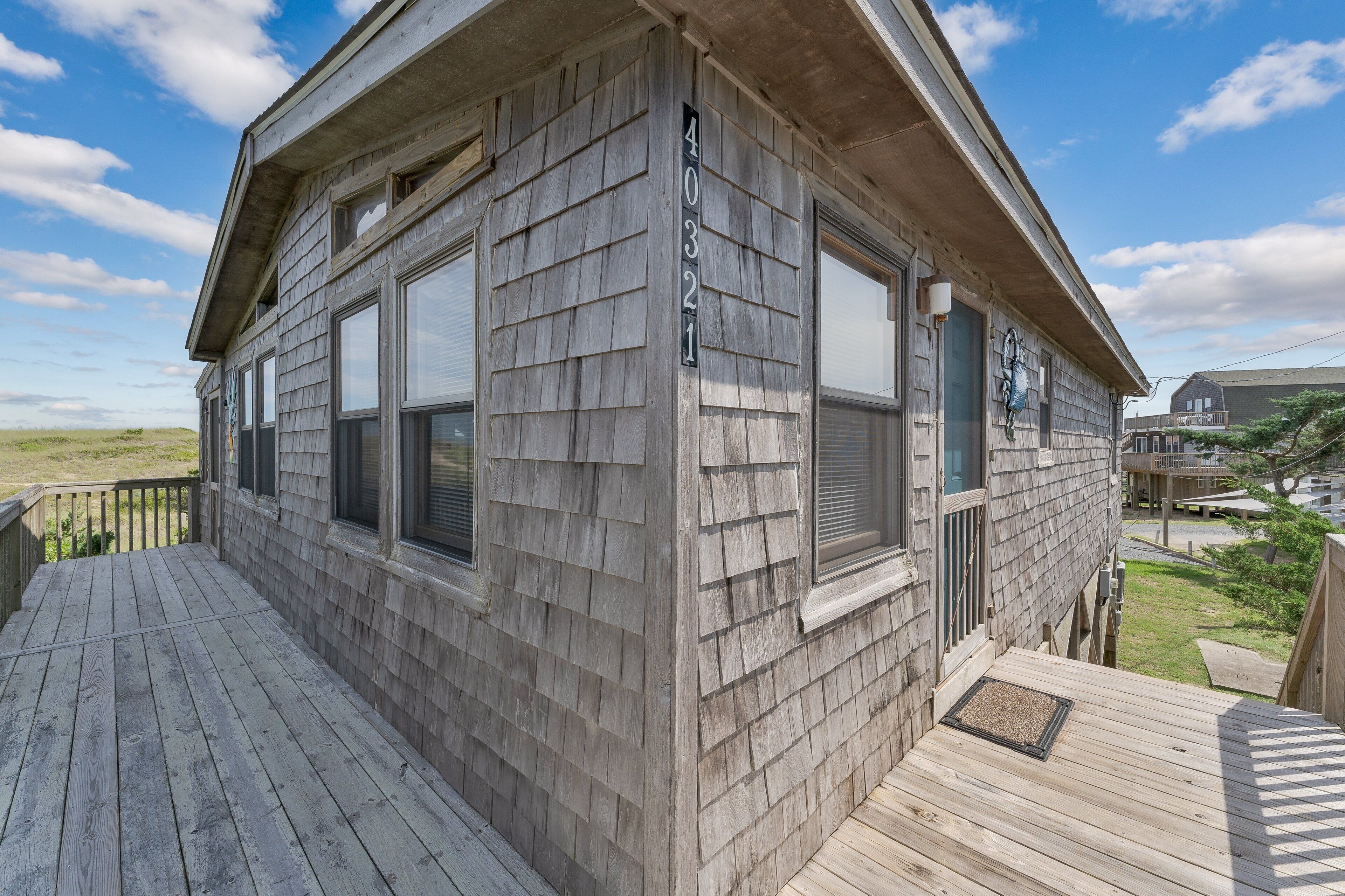 A wooden house with a number '40321' on the side, a deck, and a view of the surrounding area.