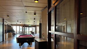 A spacious indoor area with a pool table, seating, and a stone fireplace.