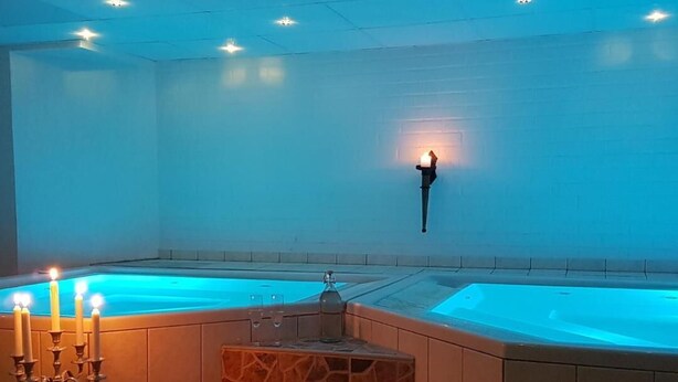 A spa area with two hot tubs, a seating area with a candelabra, and a wall-mounted light fixture.