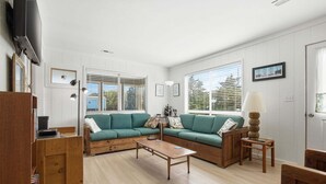 Una sala de estar con un sofá modular, una mesa de centro, un televisor y una lámpara.