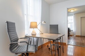 Une chambre moderne avec une table en bois, deux chaises, une lampe et une vue sur un coin cuisine.