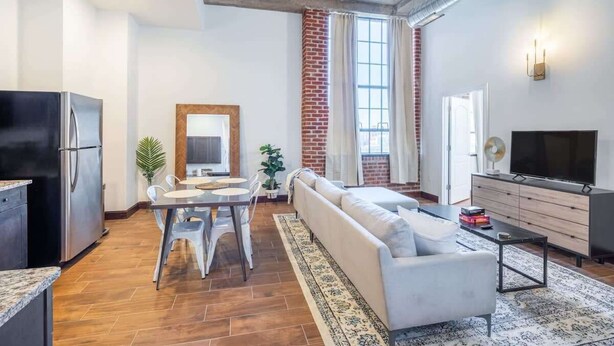 Een moderne woonkamer met een bank, eettafel, stoelen, een televisie en een koelkast.