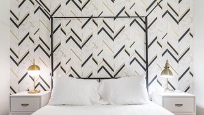 Een bed met witte beddengoed, een zwart metalen hoofdbord en twee nachtkastjes met lampen.