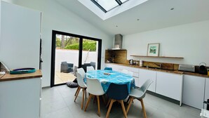 Una cocina moderna con tragaluz, un comedor con mantel azul y vistas al exterior.