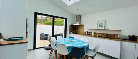Cozinha moderna com claraboia, área de jantar com toalha de mesa azul e vista para o exterior.