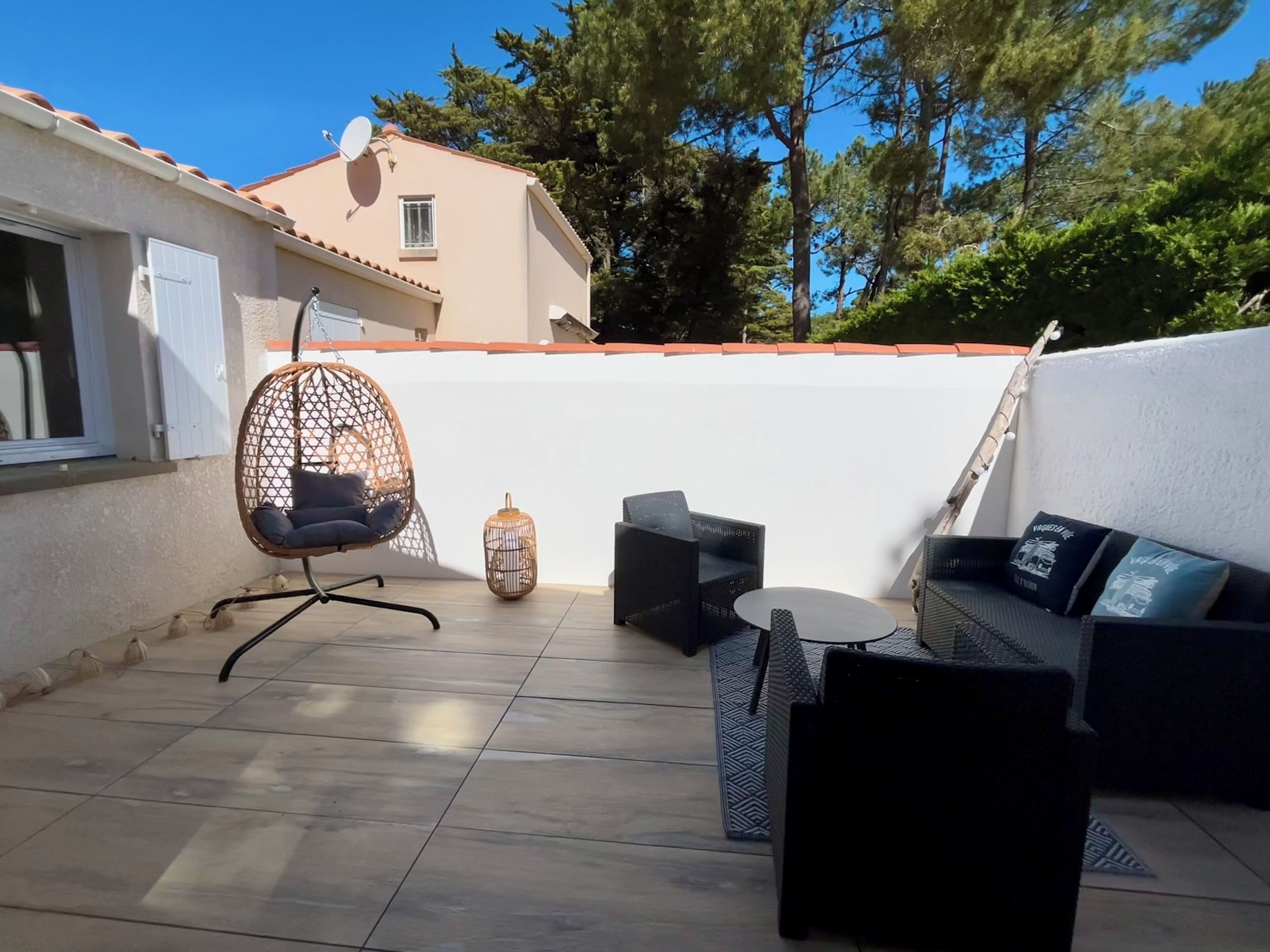 Eine Terrasse mit Hängesessel, kleinem Tisch und zwei Sofas.