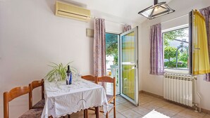 A dining area with a table set for two, chairs, a potted plant, and a view through a glass door to the outside. - Milka in Medulin - Istrien / Milka in Medulin - Appartement für 2-4 Personen (Medulin)