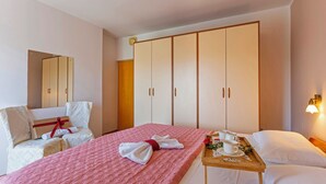 A hotel room with a bed, a wooden nightstand with a tray of breakfast items, a wardrobe, and a mirror on the wall.