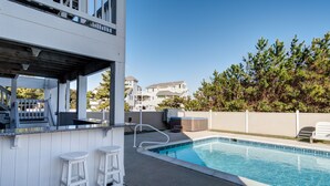 A pool area with a bar and two stools, surrounded by a fence and trees. - 4052 - Mirth N Mist II - Spacious Duck Escape | Pool & Sleeps 17 (Duck)