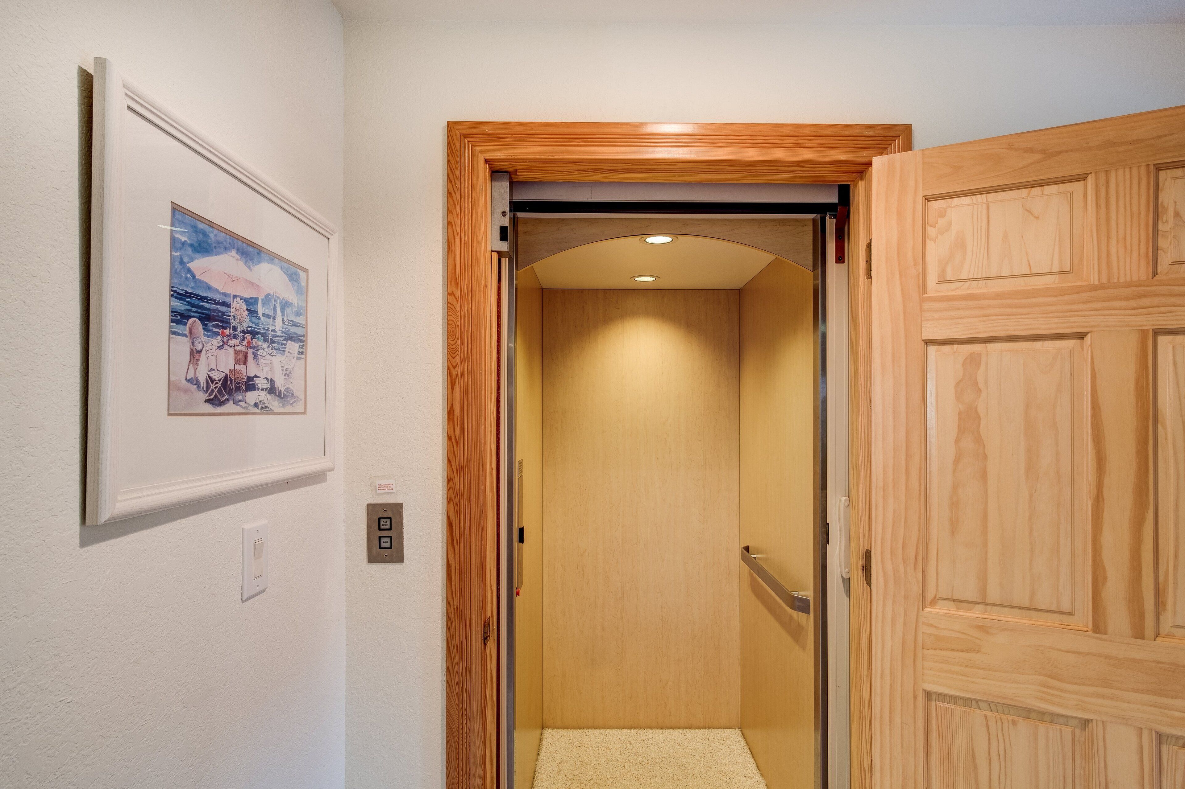 A narrow hallway with a wooden door on the right and a framed picture on the left.