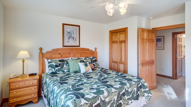 A bedroom with a bed, wooden nightstand, ceiling fan, and wooden doors. - 4052 - Mirth N Mist II - Spacious Duck Escape | Pool & Sleeps 17 (Duck)