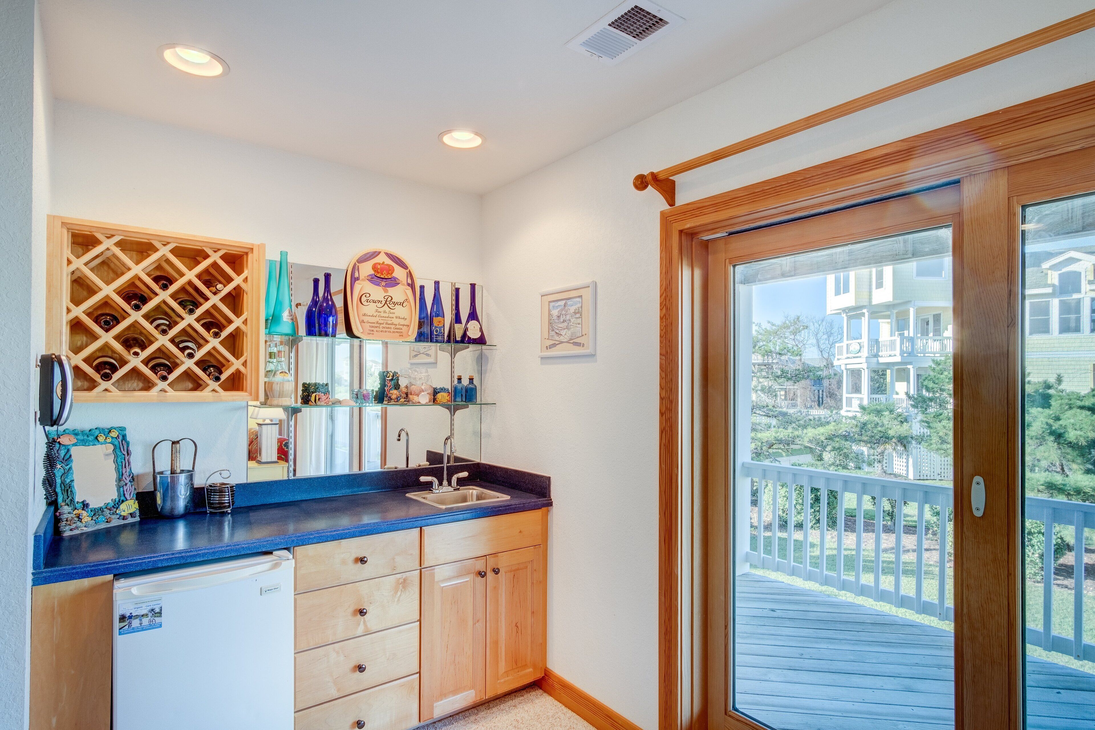 A kitchen with a built-in wine rack, a sink, and a view of the backyard through a sliding glass door.