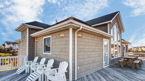 A house with a deck, white Adirondack chairs, and a wooden table. - 4052 - Mirth N Mist II - Spacious Duck Escape | Pool & Sleeps 17 (Duck)