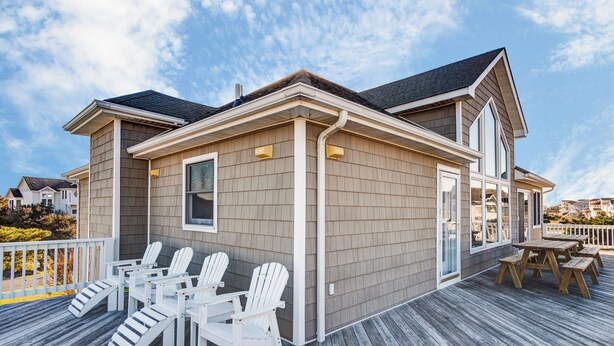 A house with a deck, white Adirondack chairs, and a wooden table. - 4052 - Mirth N Mist II - Spacious Duck Escape | Pool & Sleeps 17 (Duck)