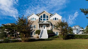 A large, two-story house with a central entrance, surrounded by a well-maintained lawn and trees. - 4052 - Mirth N Mist II - Spacious Duck Escape | Pool & Sleeps 17 (Duck)