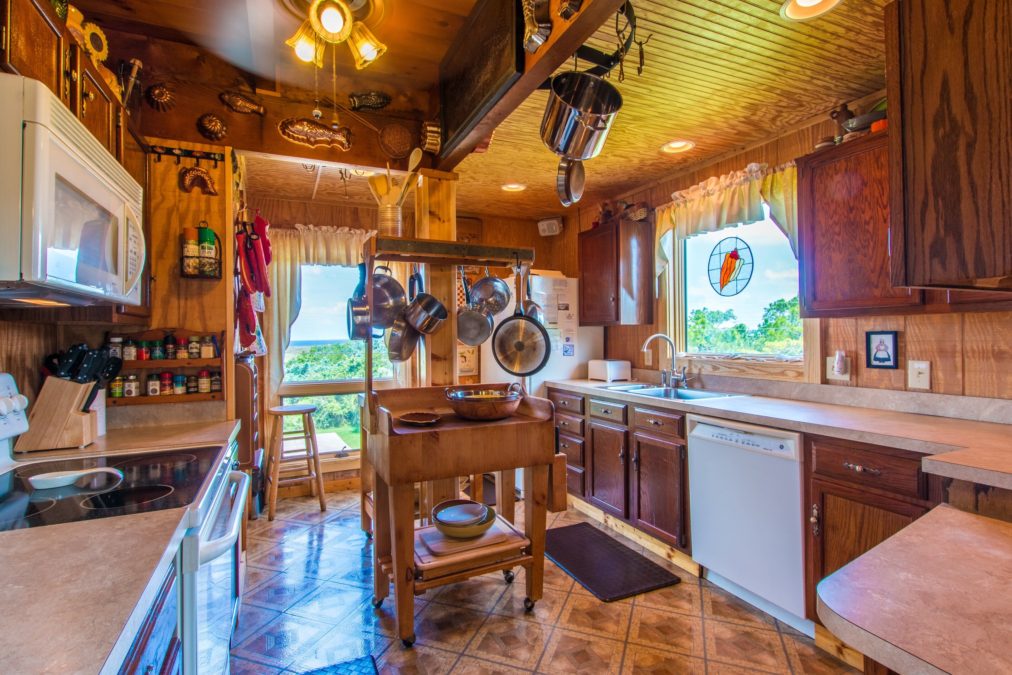 A kitchen with wooden cabinets, a microwave, a dishwasher, and hanging pots.