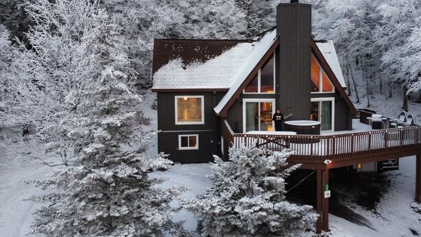 A cabin with a deck, surrounded by snow-covered trees. - 6BR Mtn House, Spectacular Valley and Sunset Views, Rec Room, Hot Tub, Fire Pit (Snowshoe)