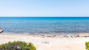 A beach with clear blue water and a sandy shore.