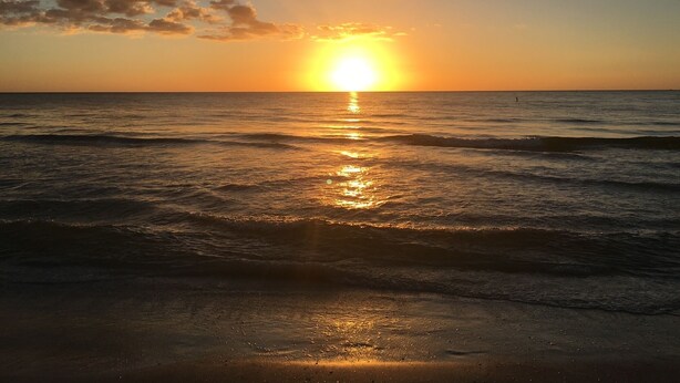 Atardecer sobre el océano con olas que reflejan la luz del sol.