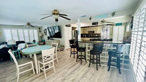 Amplia sala de estar con mesa de comedor, sillas y una zona de cocina con barra.