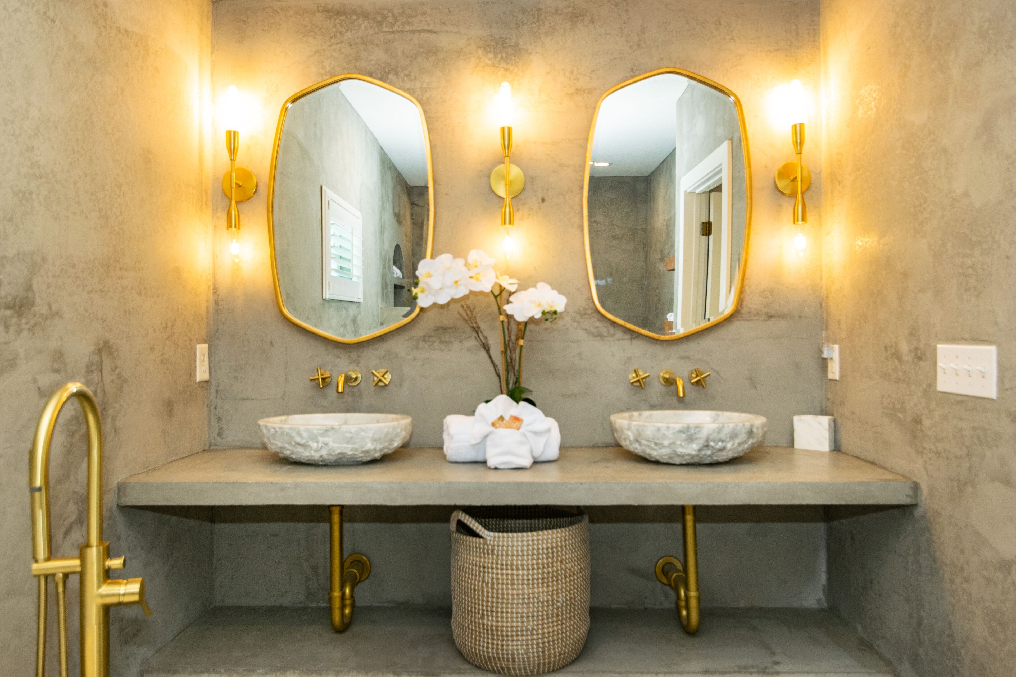 A bathroom with two sinks, a large mirror, and wall-mounted lights.