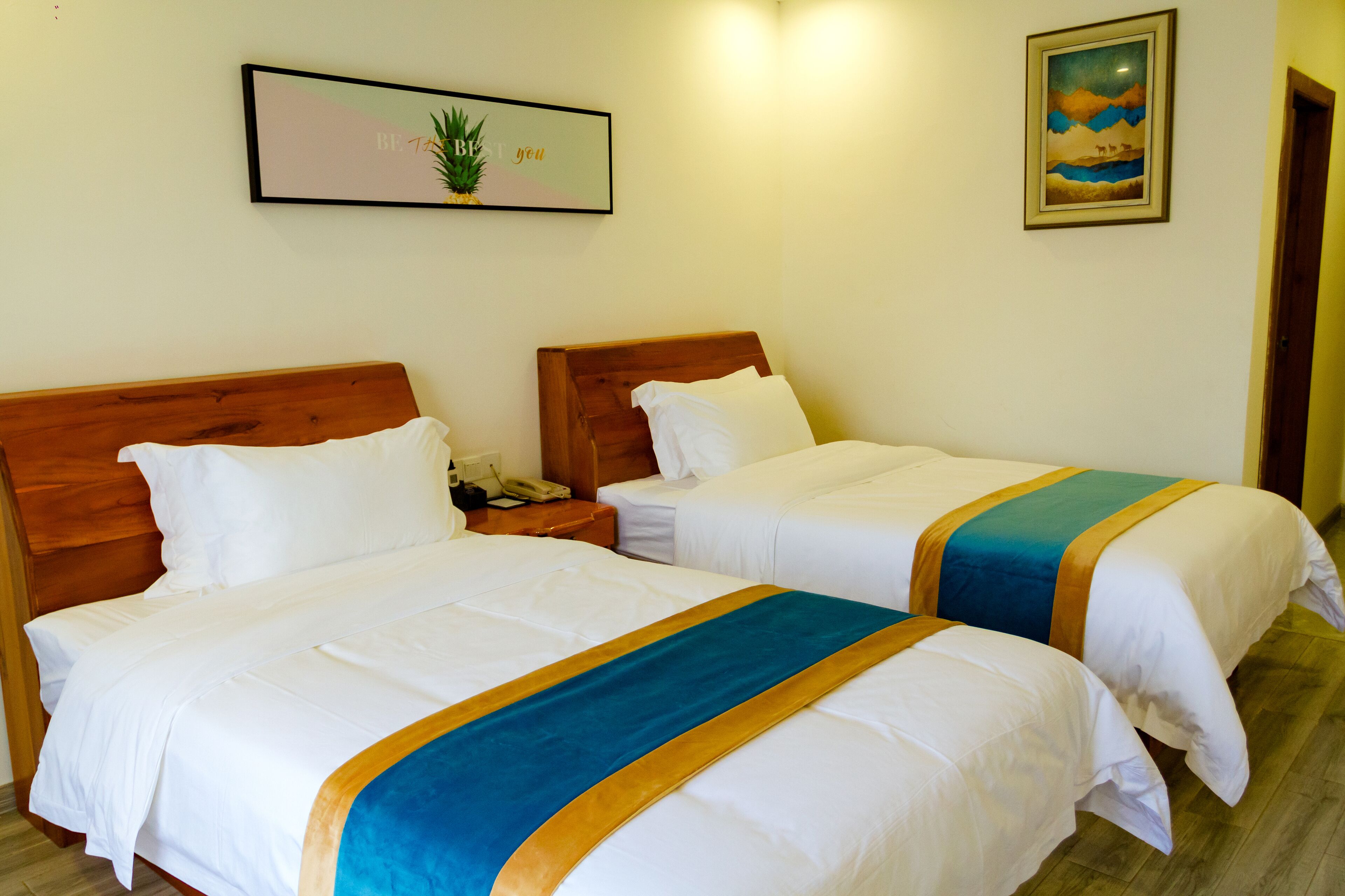 Two single beds with wooden headboards, white bedding, and a blue and gold striped runner.