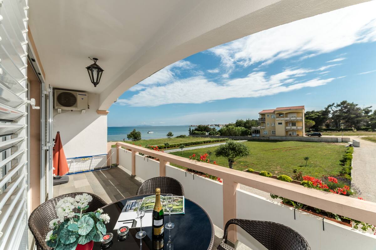 Un balcon avec une table dressée pour deux personnes, offrant une vue sur la mer.