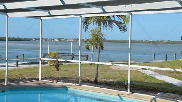 Un espace piscine offrant une vue sur l’eau et les palmiers.