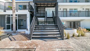 Un immeuble à plusieurs étages doté d’un escalier central, d’un espace extérieur aménagé pour s’asseoir et d’un espace piscine.
