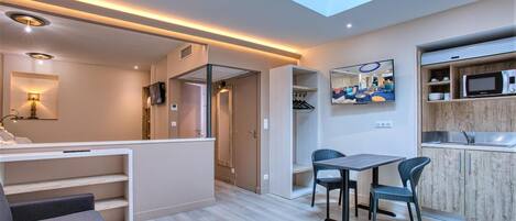 A modern interior with a dining area, kitchen, and a skylight.
