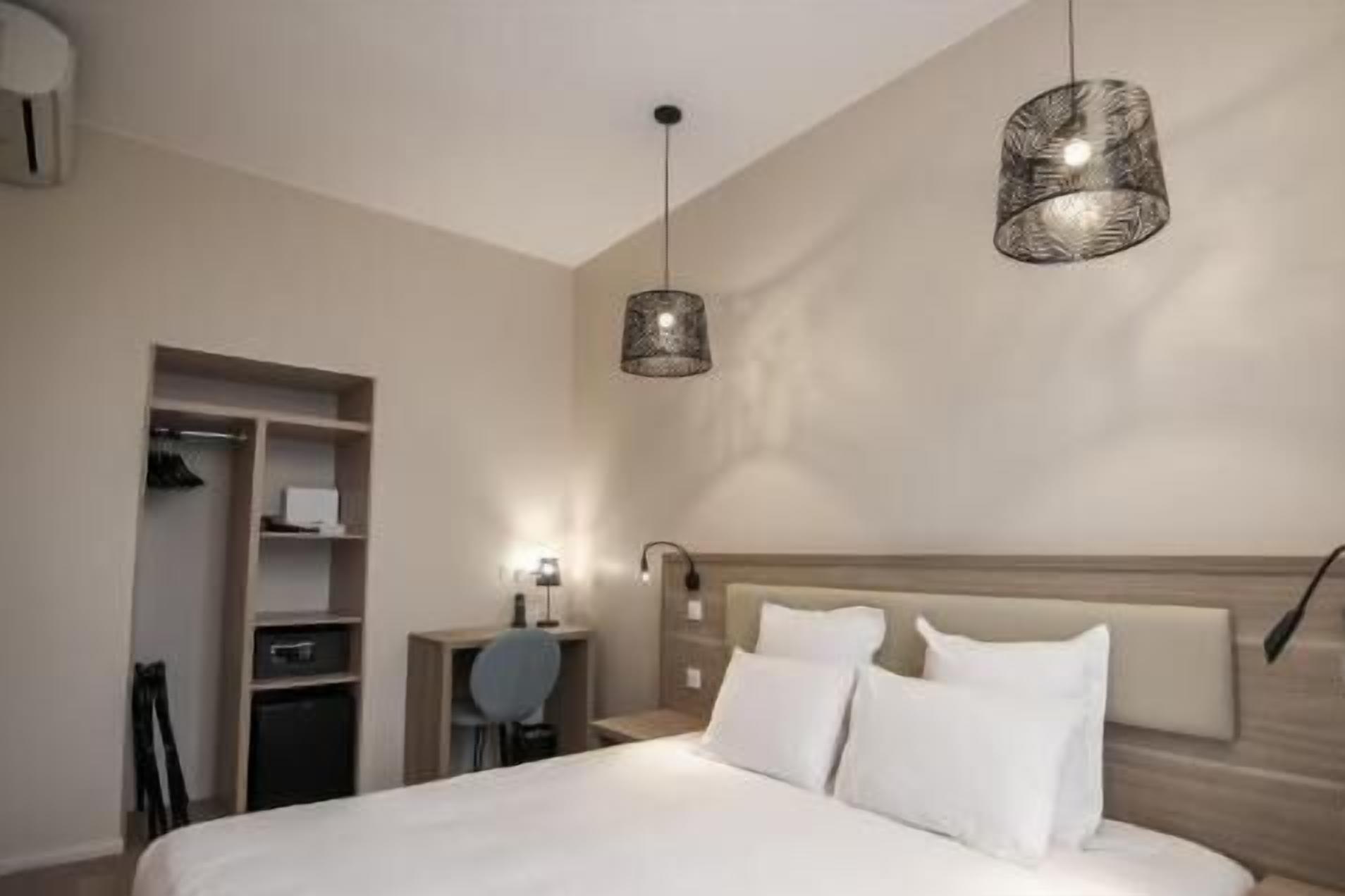 A bedroom with a bed, a nightstand, a desk, and a wardrobe.
