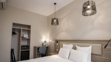 A bedroom with a bed, a nightstand, a desk, and a wardrobe.
