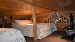 Un dormitorio cálido en el ático con dos camas, techo de madera y vista al exterior a través de una ventana.