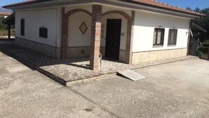 A single-story building with a tiled roof, a stone-paved entrance, and a small porch area.