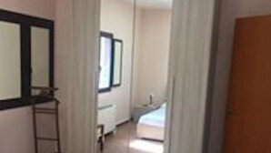 A room with a bed, a wardrobe, and a mirror on the wall.