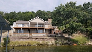 A two-story house with a balcony, located near a body of water. - LAKEFRONT PADDLEBOARD KAYAK WATERMAT SWIMMING FIREPIT GRILLING SUNDECK FISHING  (Roach)