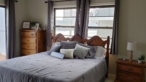 A bedroom with a bed, dresser, nightstand, and a window with curtains. - LAKEFRONT PADDLEBOARD KAYAK WATERMAT SWIMMING FIREPIT GRILLING SUNDECK FISHING  (Roach)