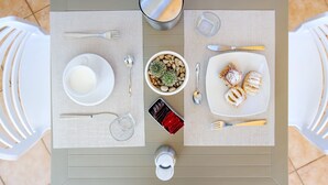 A table set for two with a bowl of nuts, a plate of pastries, a glass of water, and a small container. - Cala di Ponente (San Vito Lo Capo)