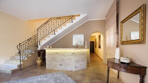 A spacious foyer with a staircase, a reception desk, and a large mirror on the wall. - Cala di Ponente (San Vito Lo Capo)